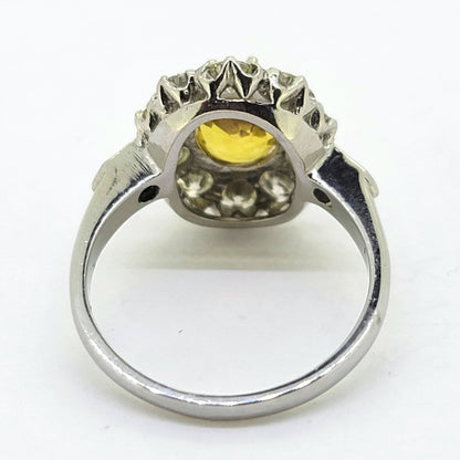 An oval yellow sapphire and round diamond cluster ring in platinum