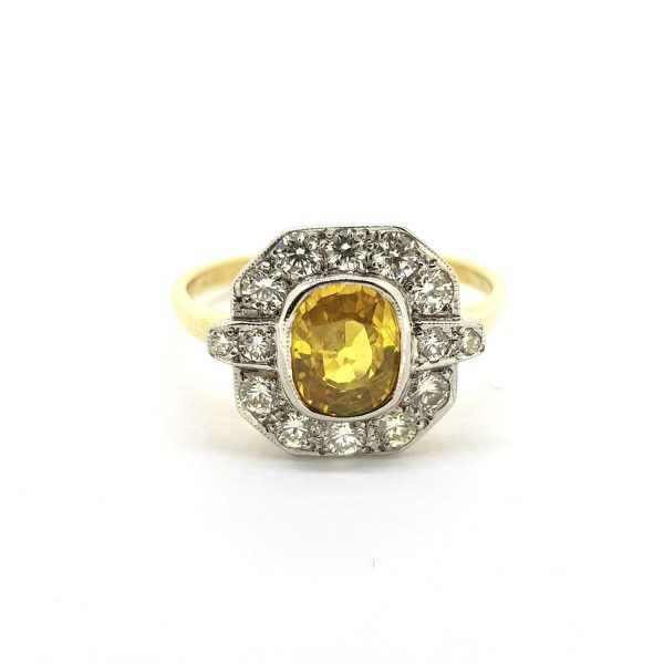 Yellow Sapphire and Diamond Cluster Ring; central 1.50ct oval yellow sapphire within a geometric diamond-set surround totalling 0.55cts, in 18ct gold