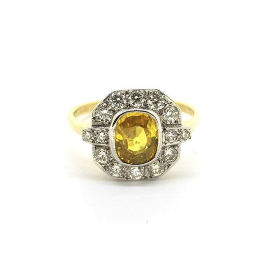 Yellow Sapphire and Diamond Cluster Ring; central 1.50ct oval yellow sapphire within a geometric diamond-set surround totalling 0.55cts, in 18ct gold