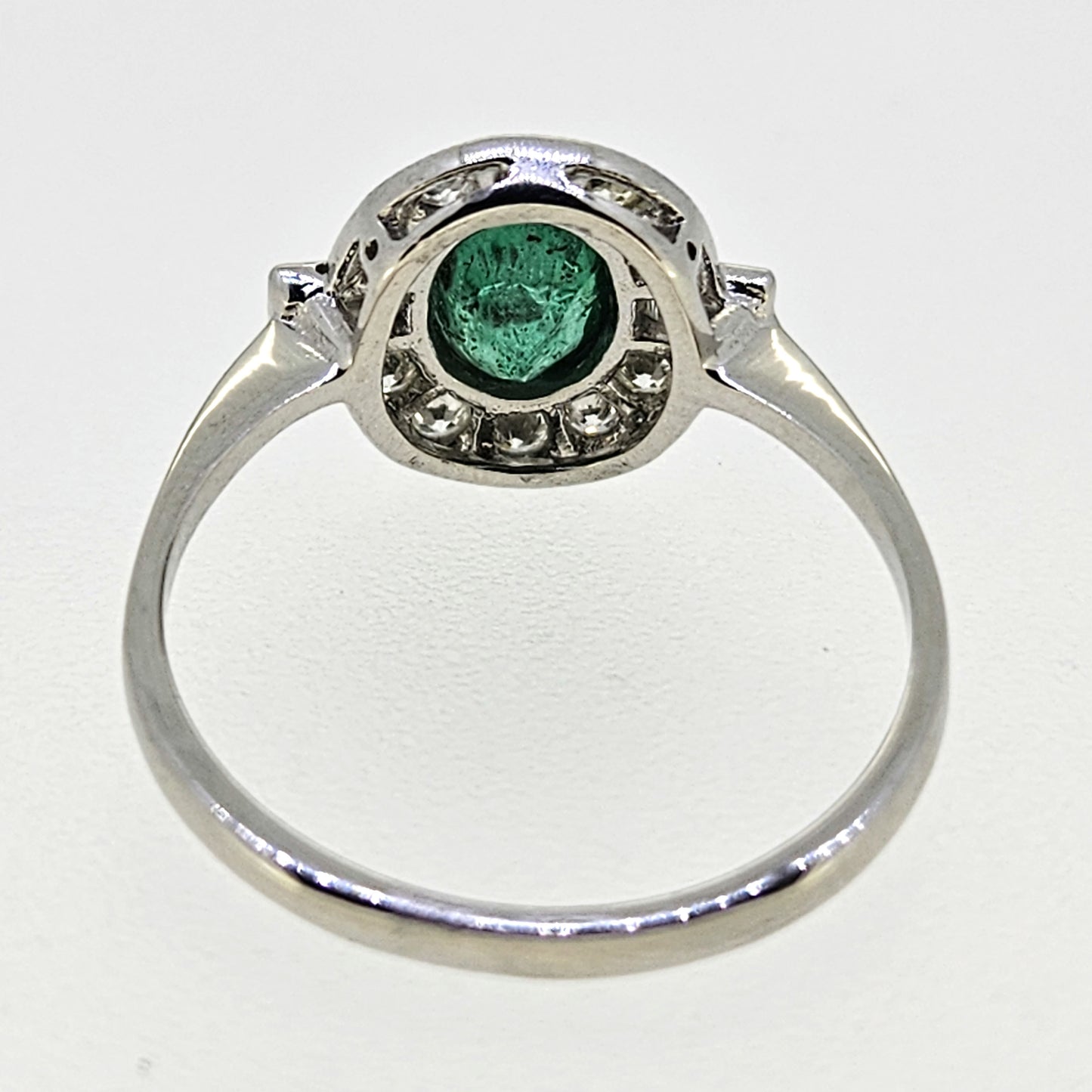 An oval emerald and diamond cluster ring in platinum
