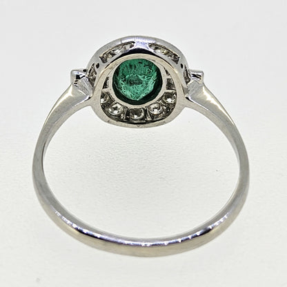 An oval emerald and diamond cluster ring in platinum