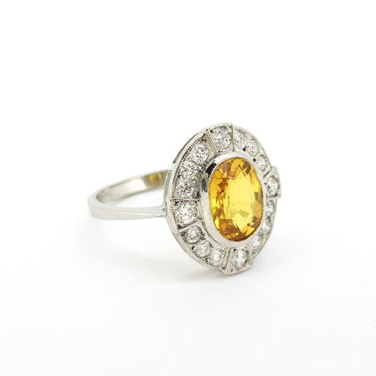 Yellow Sapphire and Diamond Oval Cluster Ring in Platinum; central 2.60ct oval yellow sapphire within a 0.40cts round brilliant cut diamonds compass style surround