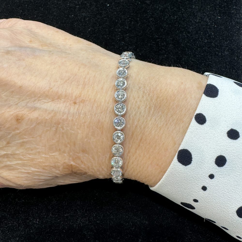 Diamond Line Tennis Bracelet in 18ct Gold, 32 round brilliant-cut diamonds totalling 6.47 carats in individual bezel settings with delicate millegrain edges
