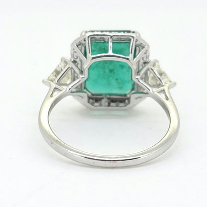 3.85ct Emerald and Diamond Cluster Ring with Trillion Diamond Sides, 3.85ct emerald-cut emerald within brilliant-cut diamond border with trillion-cut diamond to each side in 18ct white gold