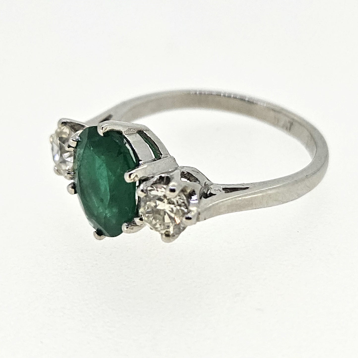 A three stone oval emerald and round diamond ring in platinum