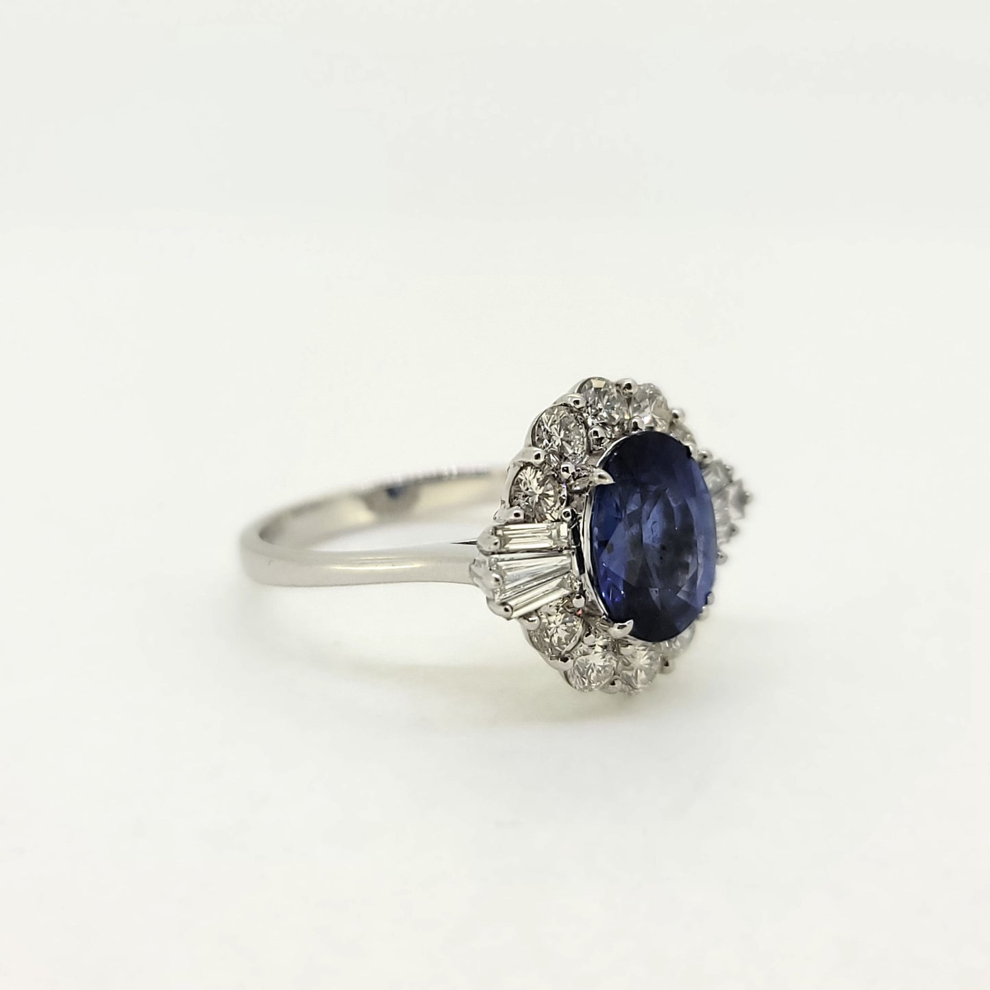 An oval sapphire, brilliant cut and baguette cut diamond cluster ring in white gold