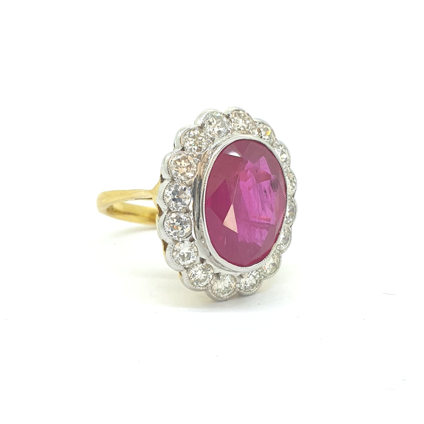 An oval ruby and round diamond scalloped edge cluster ring in yellow and white gold