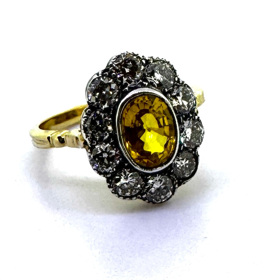 An oval yellow sapphire and round diamond cluster ring in yellow and white gold