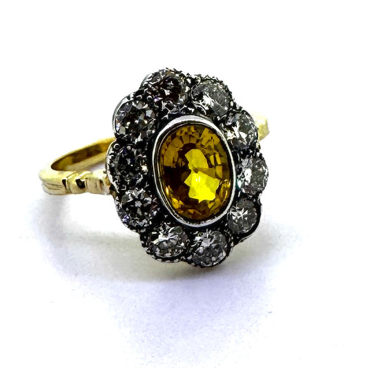 An oval yellow sapphire and round diamond cluster ring in yellow and white gold