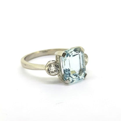 Aquamarine and Diamond Three Stone Ring in Platinum; central claw-set 2.80 carat emerald-cut aquamarine flanked by 0.50cts collet-set round brilliant-cut diamonds