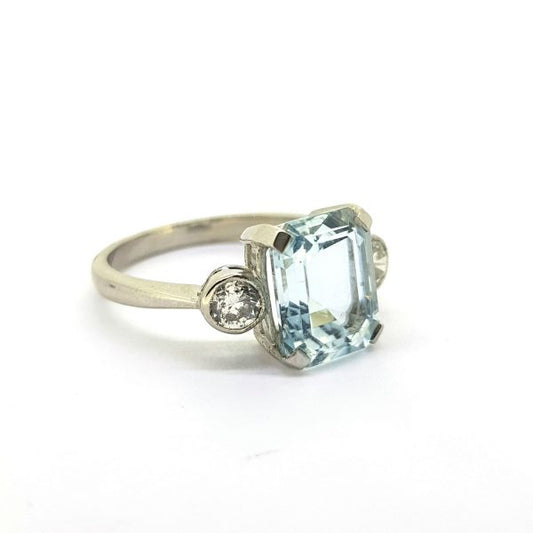 Aquamarine and Diamond Three Stone Ring in Platinum; central claw-set 2.80 carat emerald-cut aquamarine flanked by 0.50cts collet-set round brilliant-cut diamonds