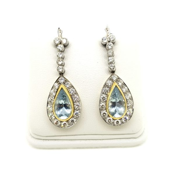 Aquamarine and Diamond Cluster Drop Earrings; featuring 4cts pear aquamarines with yellow gold borders and surrounded by diamonds, suspended from diamond-set drops, in 18ct white gold