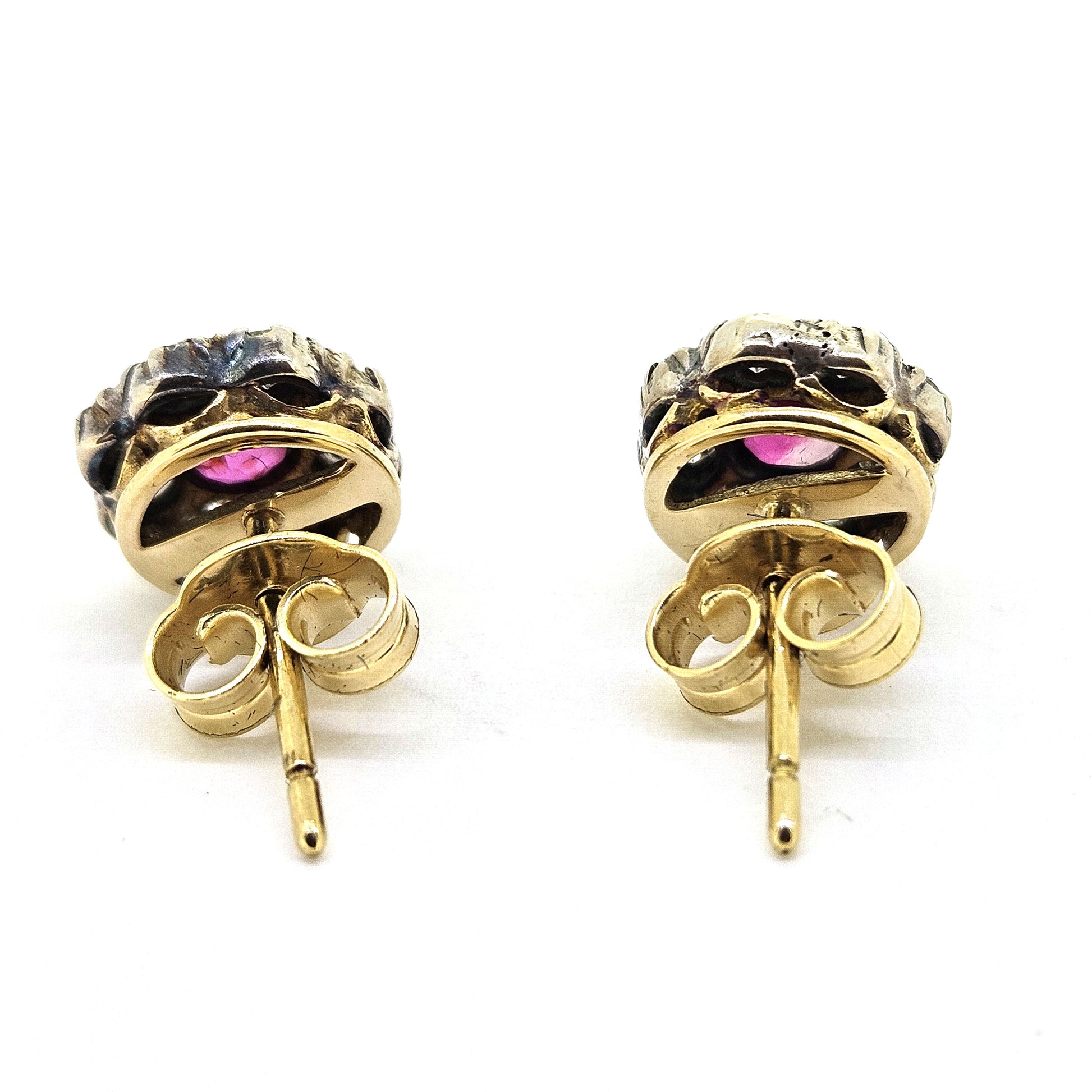 Ruby and diamond cluster earrings in gold and silver, viewed from behind, on a white background