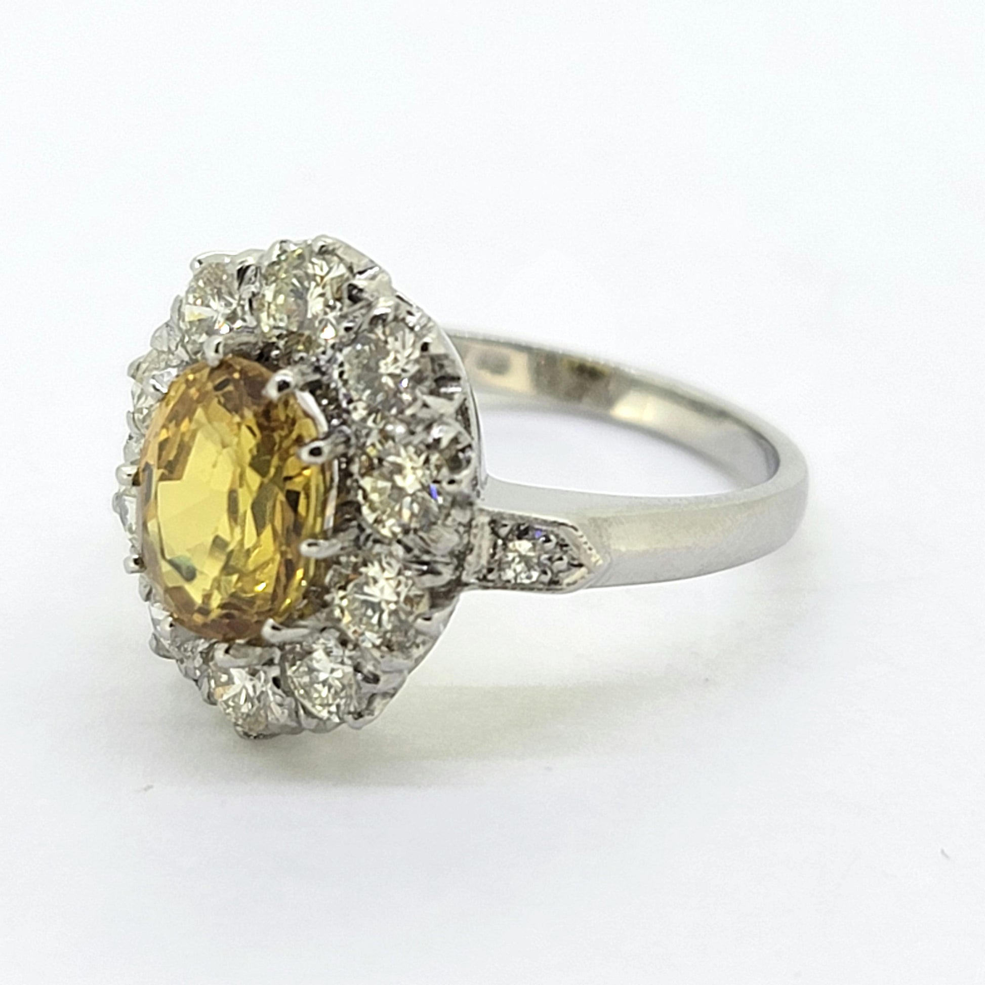 An oval yellow sapphire and round diamond cluster ring in platinum