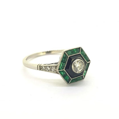 Vintage Art Deco Style Emerald, Diamond and Onyx Ring; 0.20ct J colour VVS1 Old European cut diamond framed with calibre cut emeralds and onyx, decorated with small single cut diamonds to the shoulders, in platinum. Circa 1960s