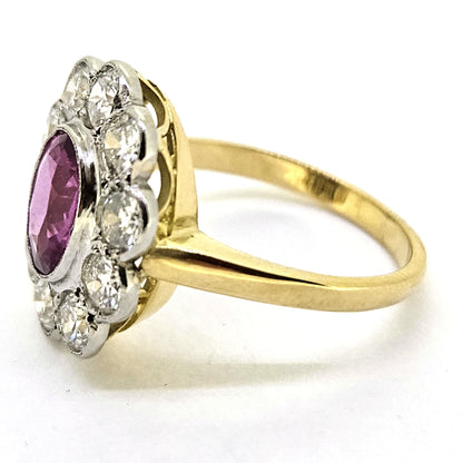 A pink sapphire and round diamond oval shaped cluster ring in yellow and white metal, on a white background