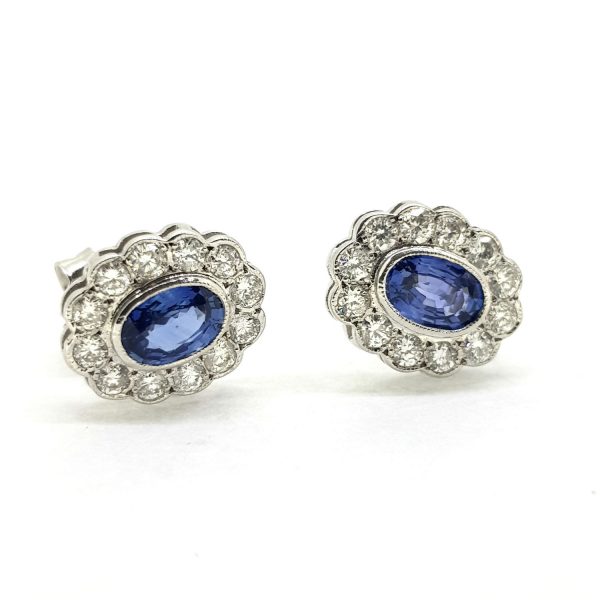 Sapphire and Diamond Oval Cluster Stud Earrings; central 1.10ct oval sapphires within 0.65ct diamond surrounds, collet set and mounted in 18ct white gold