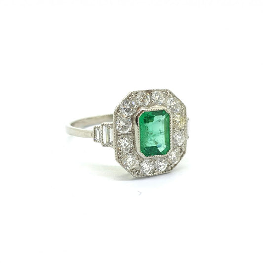 An octagonal cluster ring with an emerald centre and diamond surround, in platinum