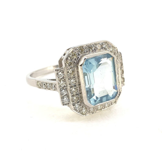 An aquamarine and diamond octagonal shaped cluster ring in white metal, against a white background