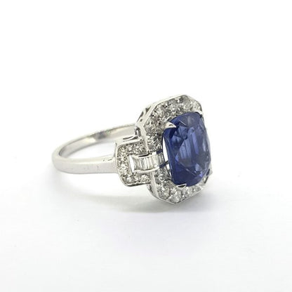 Sapphire and Diamond Cluster Dress Ring; central 3.46ct oval sapphire enclosed within a surround of 0.71cts bright white brilliant and baguette-cut diamonds with detailed 'lock' shoulders, in 18ct white gold
