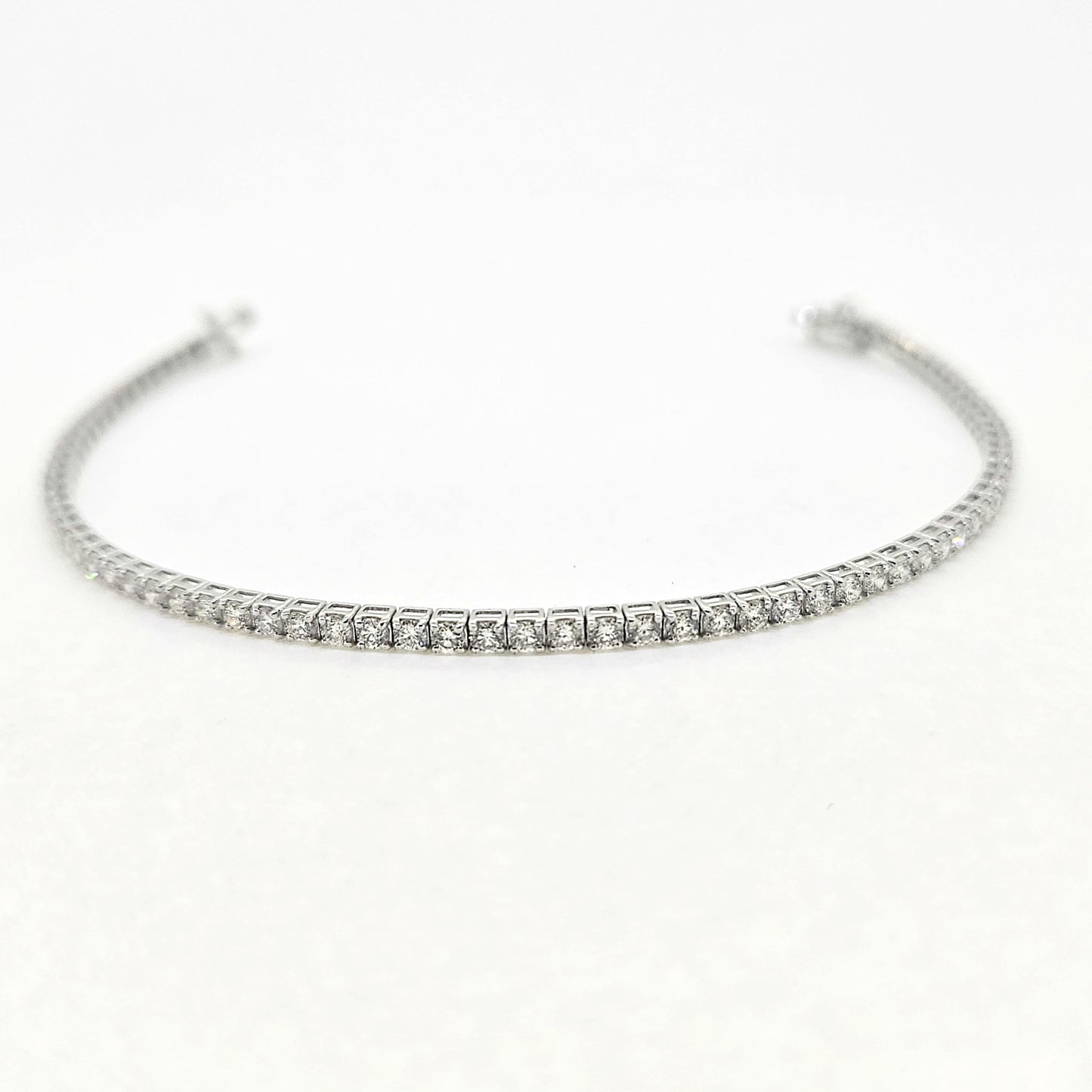 A brilliant cut diamond line bracelet, clasp open, on a white background