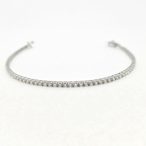A brilliant cut diamond line bracelet, clasp open, on a white background