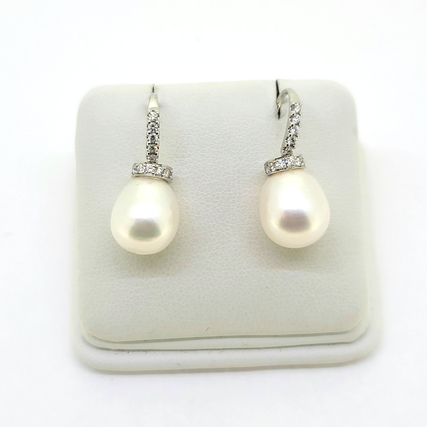 Pearl and diamond drop earrings in white gold, on an earring display pad