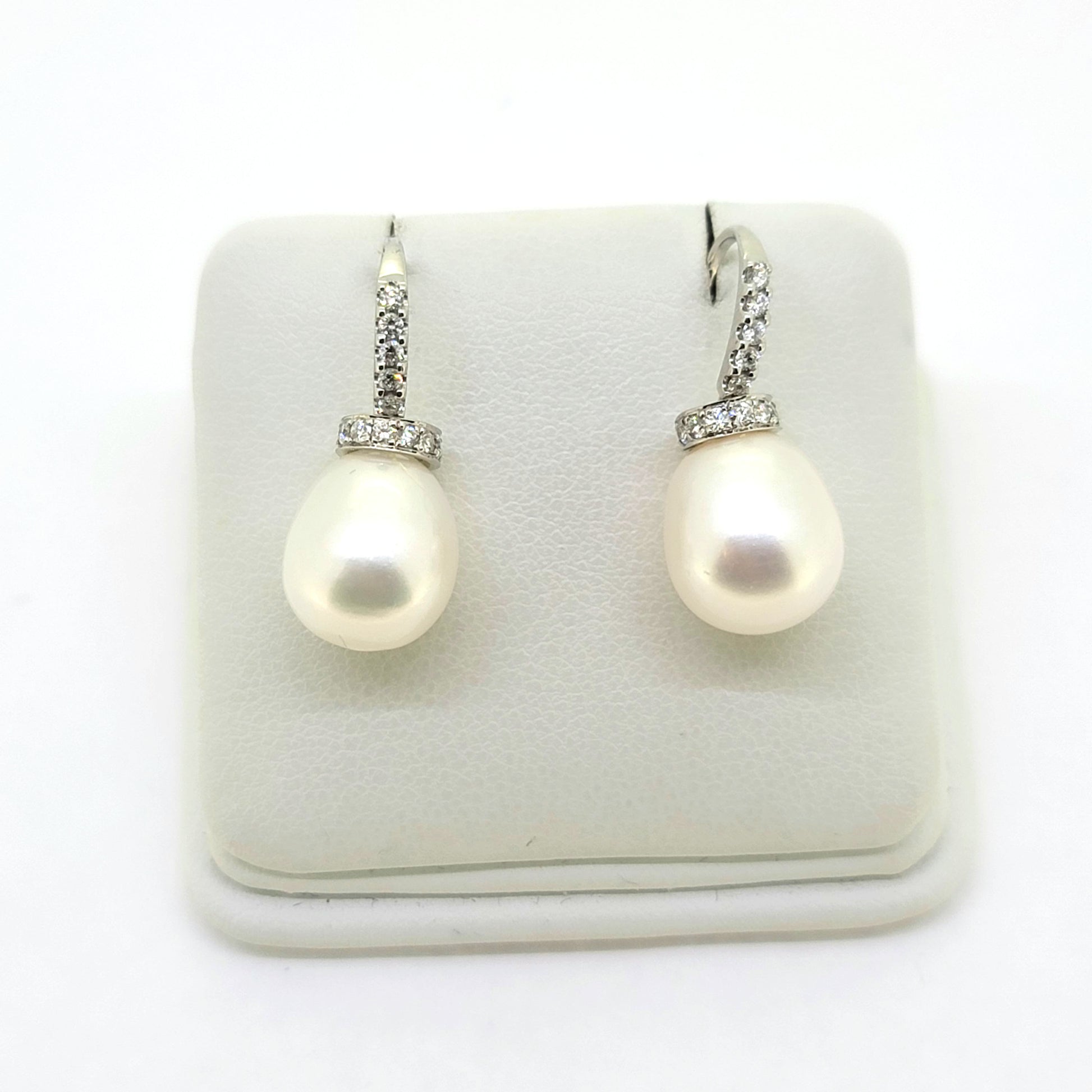 Pearl and diamond drop earrings in white gold, on an earring display pad