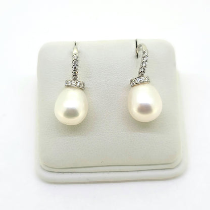 Pearl and diamond drop earrings in white gold, on an earring display pad