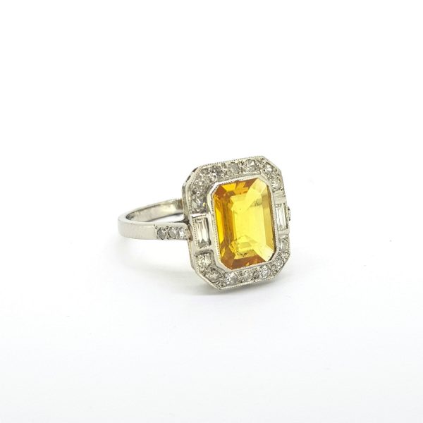 Yellow Sapphire and Diamond Cluster Dress Ring in Platinum; central 2ct emerald-cut yellow sapphire within a 0.40ct diamond halo of eight-cut and baguette-cut diamonds