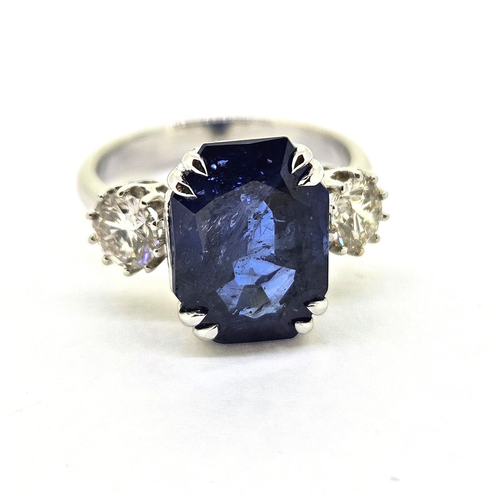 6.71ct Sapphire and Diamond Trilogy Three Stone Engagement Ring in 18ct White Gold, 6.71ct oval cushion-shaped blue sapphire flanked by 0.82cts sparkling brilliant diamonds