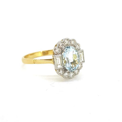 Aquamarine and Diamond Cluster Ring; central 1ct oval aquamarine with a 0.50ct baguette and brilliant-cut diamond surround, in 18ct gold
