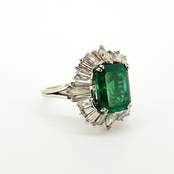 Emerald and Diamond Cluster Ballerina Ring in Platinum; central 4ct emerald-cut emerald within a 1.50ct diamond surround of tapered baguette-cut diamonds with marquise-cut diamond accents