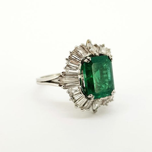 Emerald and Diamond Cluster Ballerina Ring in Platinum; central 4ct emerald-cut emerald within a 1.50ct diamond surround of tapered baguette-cut diamonds with marquise-cut diamond accents