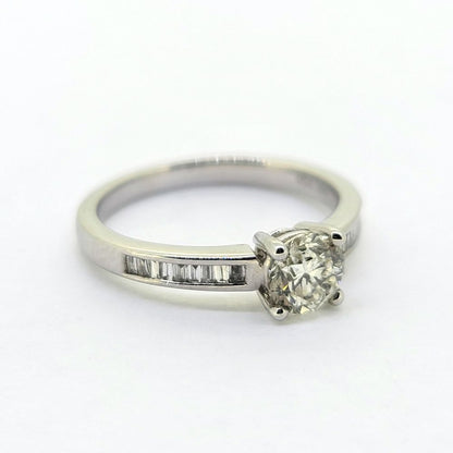 A brilliant and baguette cut diamond ring in white gold, against a white background