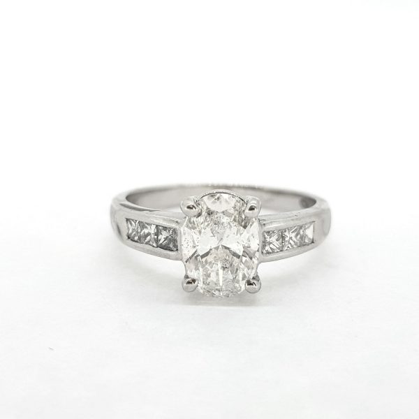 Oval Cut Diamond Engagement Ring with Princess Cut Diamond Shoulders; central 1.22ct oval cut diamond, claw set and flanked by 0.36cts channel set square princess-cut diamonds, in 18ct white gold