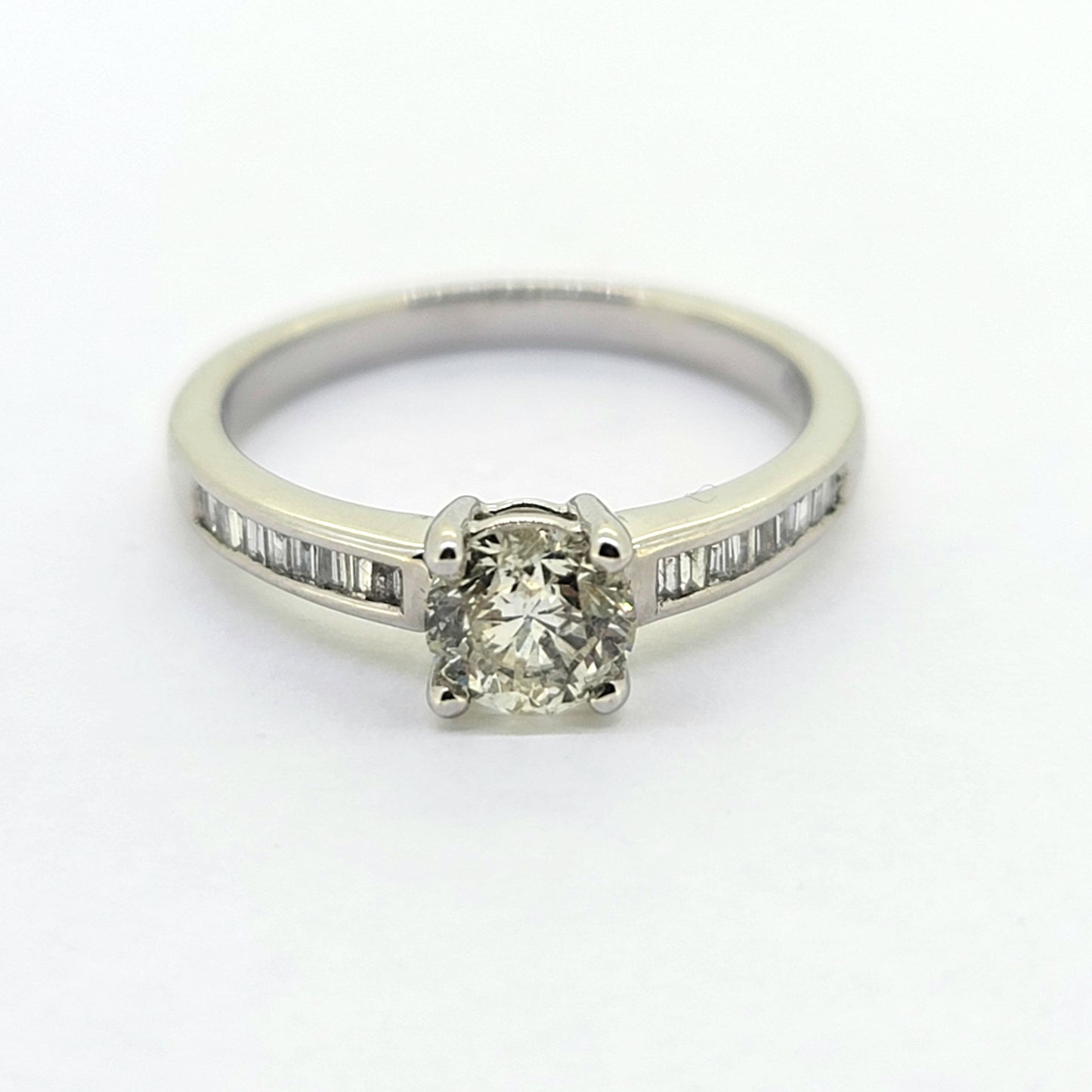 A brilliant and baguette cut diamond ring in white gold, against a white background