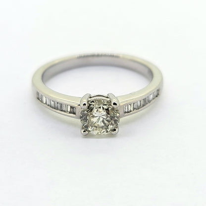 A brilliant and baguette cut diamond ring in white gold, against a white background