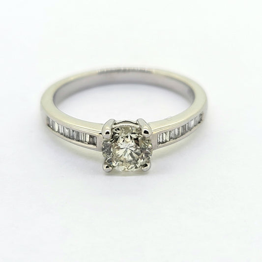 A brilliant and baguette cut diamond ring in white gold, against a white background