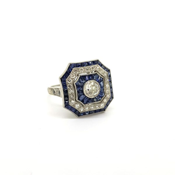 Art Deco Style Sapphire and Diamond Cluster Dress Ring in Platinum; central diamond surrounded by alternated borders of calibre-cut sapphires and diamonds
