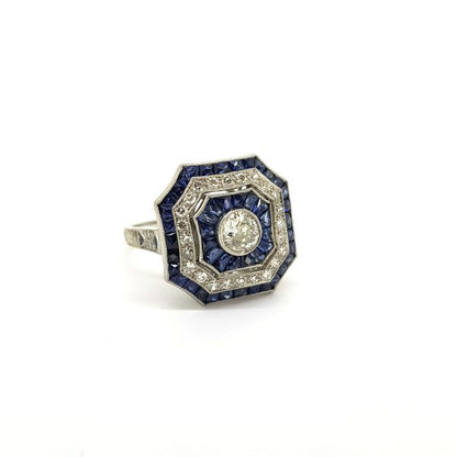 Art Deco Style Sapphire and Diamond Cluster Dress Ring in Platinum; central diamond surrounded by alternated borders of calibre-cut sapphires and diamonds