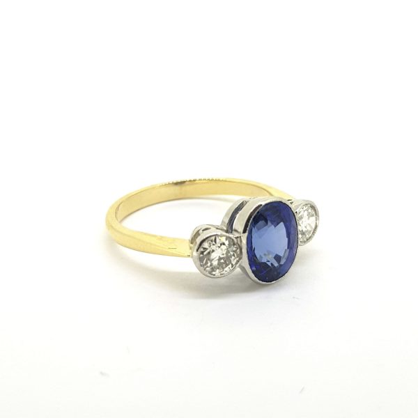 Sapphire and Diamond Three Stone Ring; central 2.25ct oval sapphire flanked by 0.65cts brilliant-cut diamonds, all collet set in platinum and mounted to a plain 18ct yellow gold band