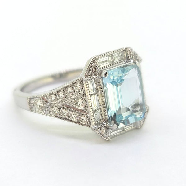 Contemporary Aquamarine and Diamond Cluster Dress Engagement Ring in 18ct White Gold, 1.85ct emerald-cut aquamarine surrounded by baguette-cut diamond halo with brilliant diamond accents to each corner with tapered diamond-set shoulders