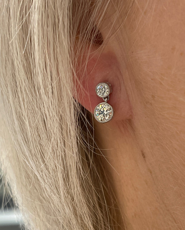 A round brilliant cut diamond double drop earring in white metal, modelled in an ear
