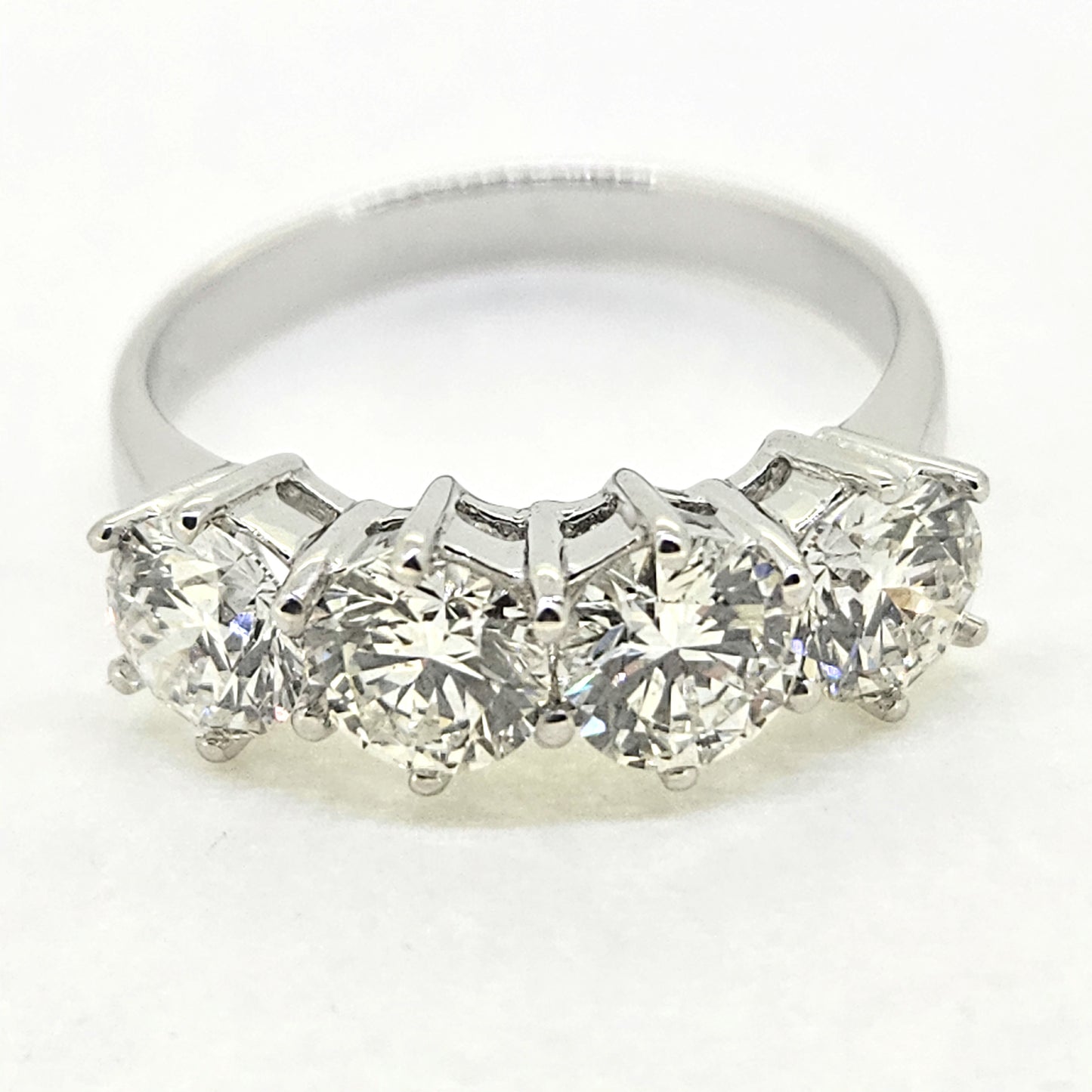 A four stone brilliant cut diamond ring in white gold, on a white background