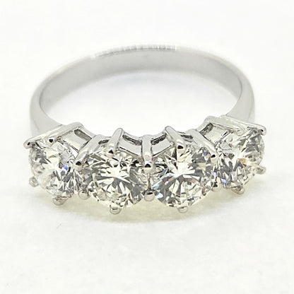 A four stone brilliant cut diamond ring in white gold, on a white background