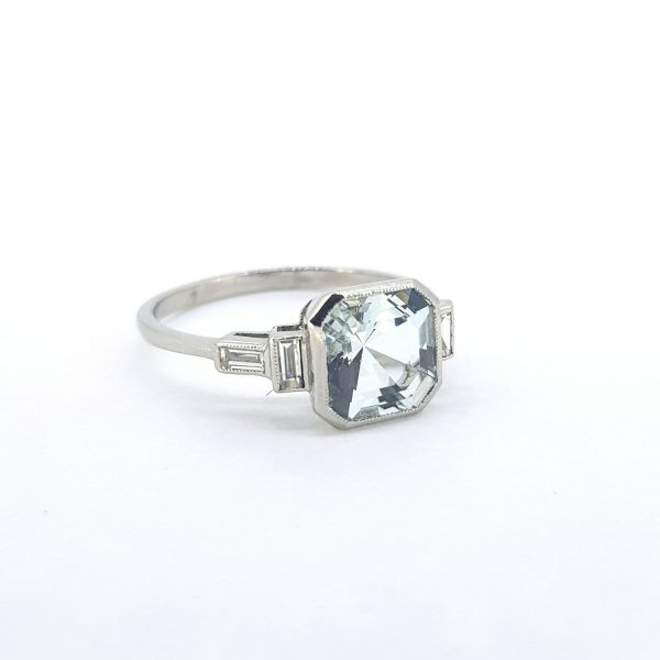Aquamarine and Baguette Diamond Dress Ring; central octagonal-cut aquamarine decorated with baguette cut diamonds to the shoulders, in 18ct white gold