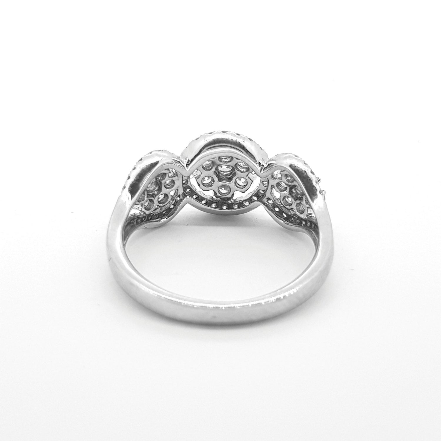 A circular triple cluster ring with round diamonds in white gold, against a white background