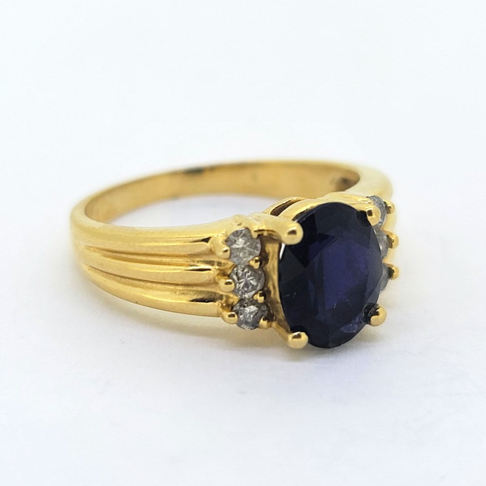 Oval Sapphire and Diamond Engagement Ring in 18ct Yellow Gold, oval blue sapphire flanked by lines of sparkling diamonds with ribbed shoulders