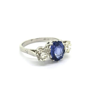 Sapphire and Diamond Three Stone Ring in Platinum; classic trilogy ring featuring a 2.65ct oval faceted sapphire flanked by 1.28cts round brilliant-cut diamonds, claw set and mounted in platinum
